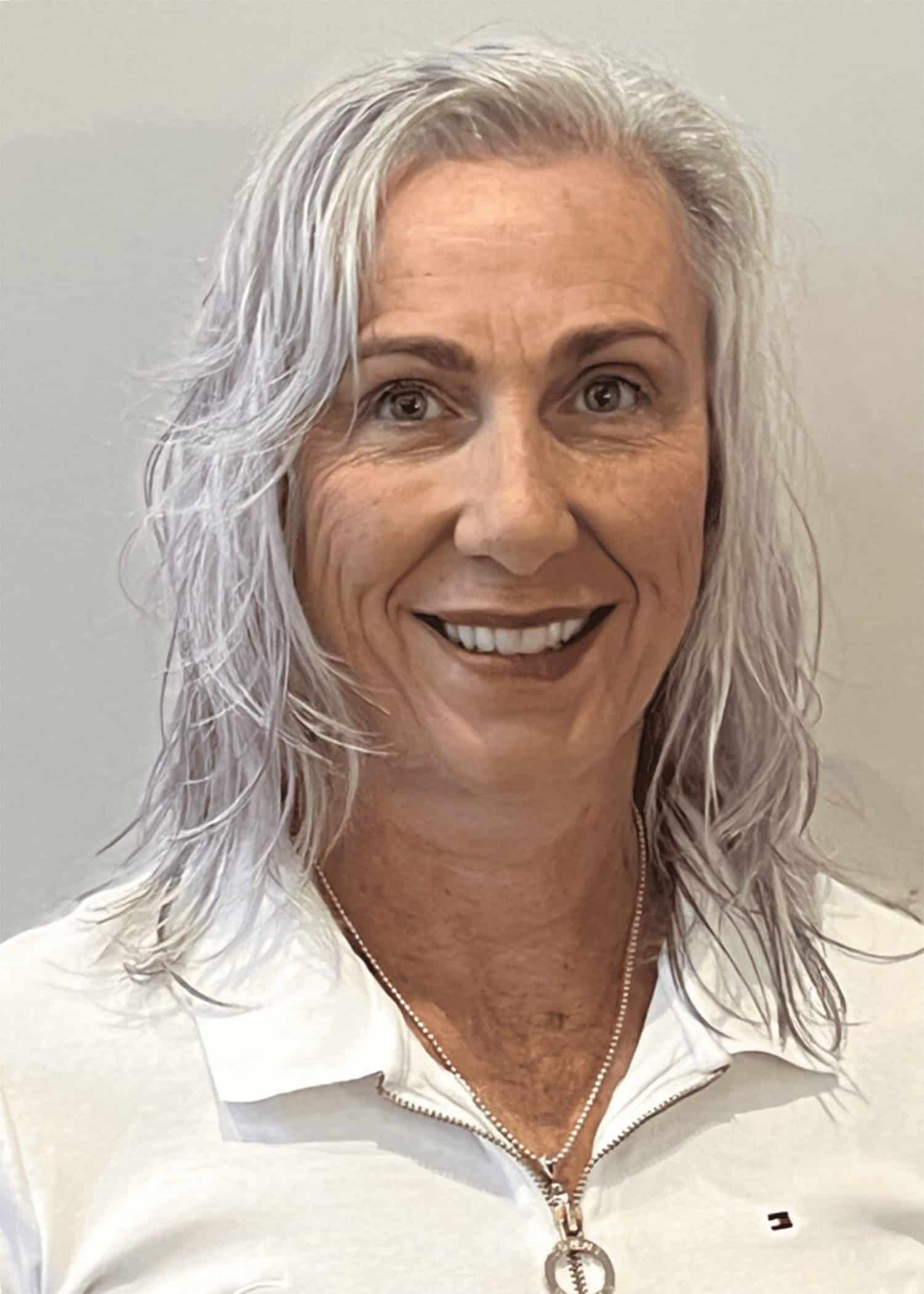 A woman, the manager of Gracious Homes, smiling with shoulder length dyed grey hair